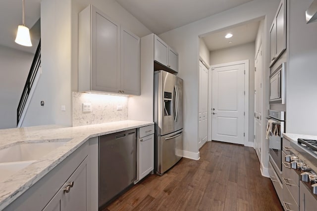 kitchen with stainless steel appliances, light stone counters, tasteful backsplash, dark hardwood / wood-style flooring, and decorative light fixtures