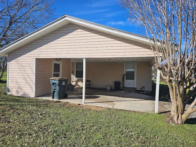 rear view of property with a carport and a yard