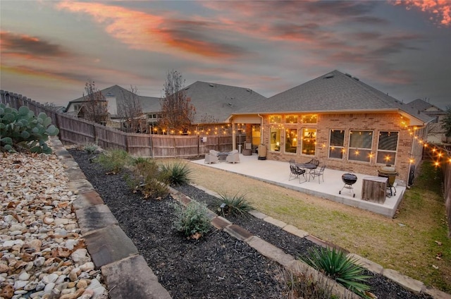 back house at dusk featuring a yard, a fire pit, and a patio