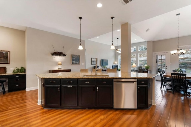 kitchen featuring sink, decorative light fixtures, stainless steel dishwasher, and an island with sink