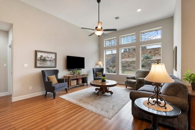 living room featuring hardwood / wood-style flooring, a towering ceiling, and ceiling fan