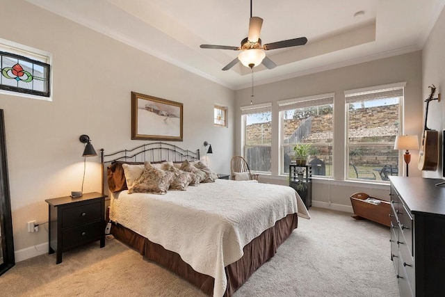 bedroom with light carpet, a tray ceiling, crown molding, and ceiling fan