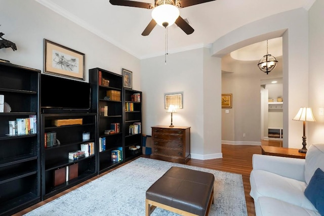 living room featuring crown molding, wood-type flooring, and ceiling fan