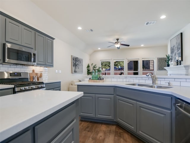 kitchen featuring gray cabinetry, sink, backsplash, and appliances with stainless steel finishes