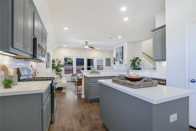 kitchen featuring dark wood-type flooring, gray cabinets, kitchen peninsula, a kitchen island, and stainless steel appliances