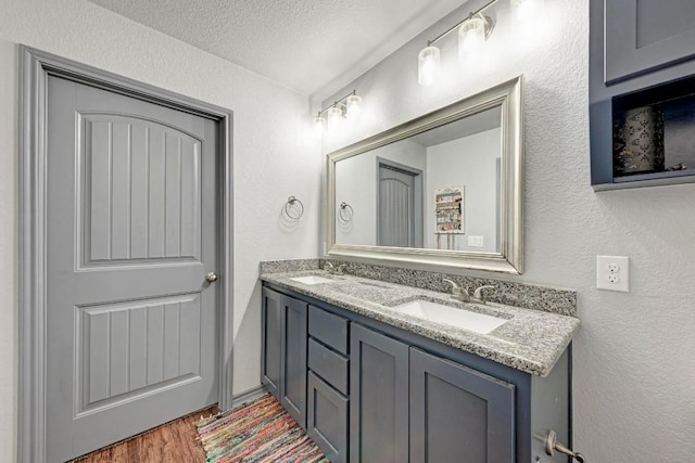 bathroom with hardwood / wood-style flooring, vanity, and a textured ceiling