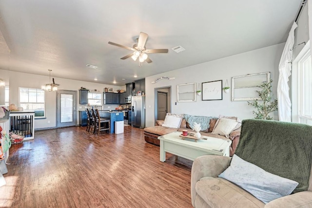 living room featuring ceiling fan with notable chandelier and dark hardwood / wood-style floors