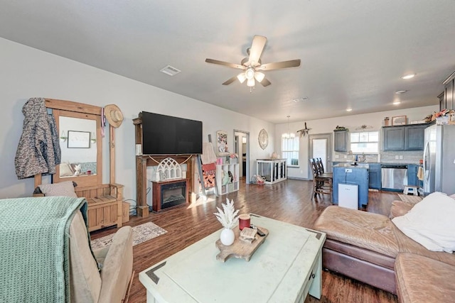 living room with ceiling fan with notable chandelier and dark wood-type flooring