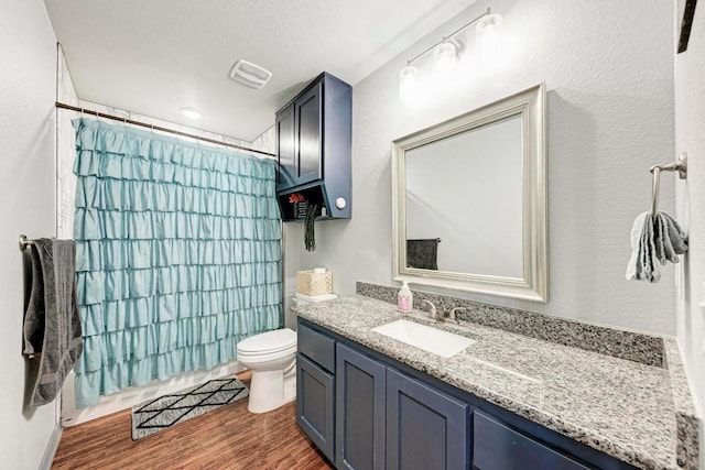 full bathroom featuring hardwood / wood-style flooring, vanity, shower / tub combo, and toilet