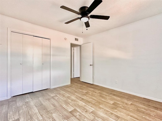 unfurnished bedroom with ceiling fan, a closet, light hardwood / wood-style flooring, and a textured ceiling