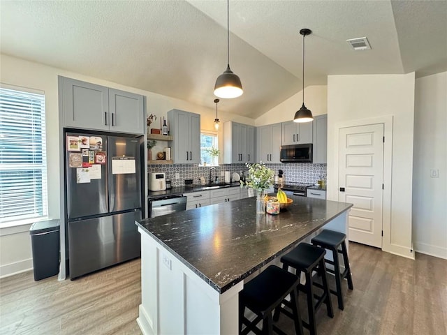 853 Cypress Ln, Cottonwood Shores, TX 78657 - kitchen featuring stainless steel appliances, gray cabinets, light wood-style floors, backsplash, and lofted ceiling