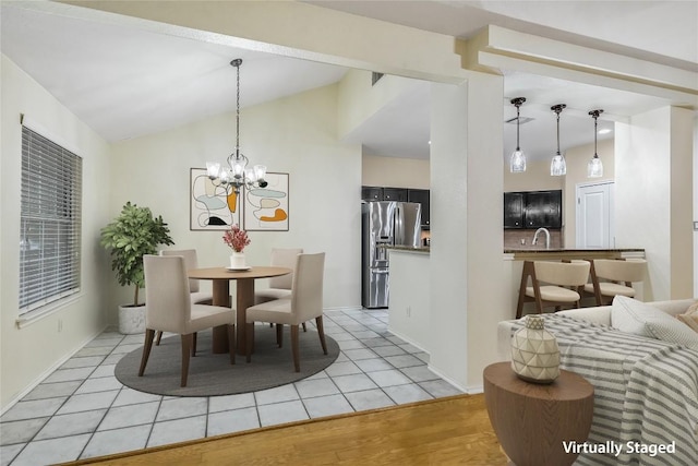 dining room with lofted ceiling, sink, a notable chandelier, and light hardwood / wood-style floors