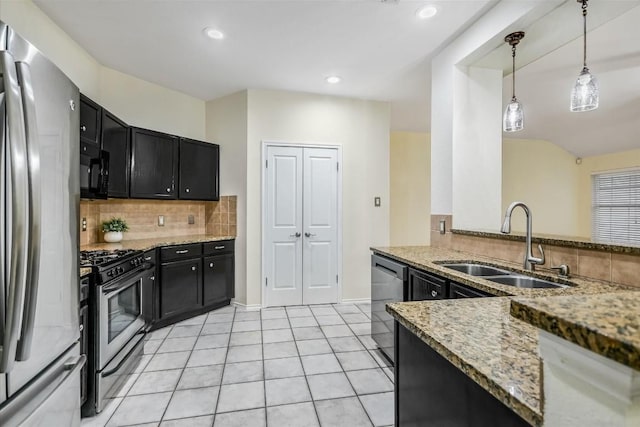 kitchen featuring appliances with stainless steel finishes, sink, backsplash, hanging light fixtures, and light stone counters