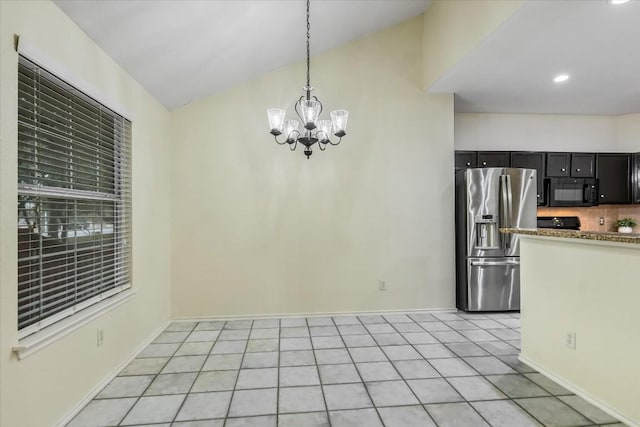 kitchen with vaulted ceiling, stainless steel fridge, backsplash, hanging light fixtures, and a notable chandelier