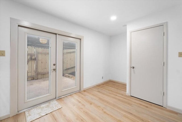 spare room with french doors and light hardwood / wood-style flooring