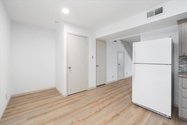 kitchen featuring light wood-type flooring, gray cabinets, tasteful backsplash, and white fridge