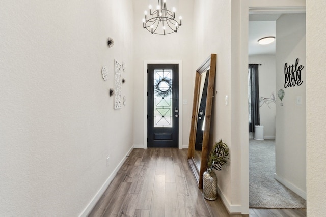 foyer entrance featuring wood-type flooring and a chandelier