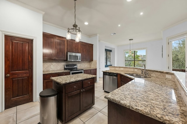 kitchen with a kitchen island, appliances with stainless steel finishes, sink, decorative backsplash, and hanging light fixtures