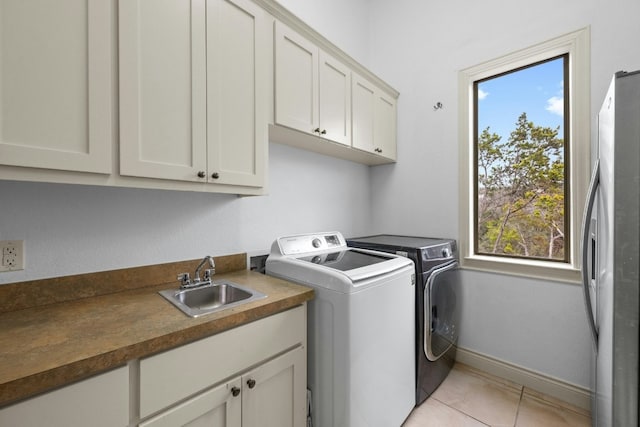 washroom with separate washer and dryer, sink, light tile patterned floors, and cabinets