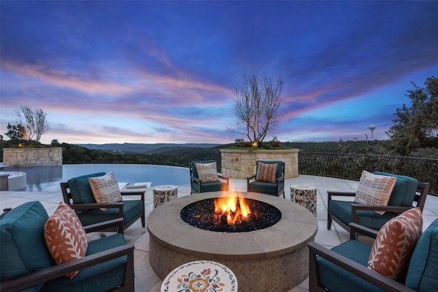 patio terrace at dusk featuring a water view and a fire pit