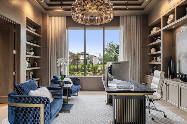 office space featuring built in shelves, a raised ceiling, and an inviting chandelier