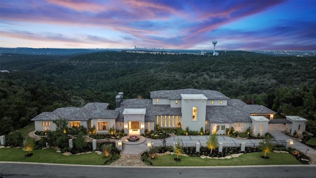 view of front of house featuring a forest view, driveway, and stucco siding