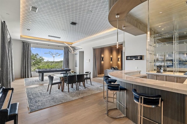 dining space with a raised ceiling and light hardwood / wood-style flooring