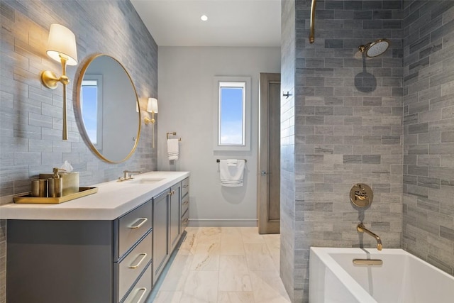 bathroom with tiled shower / bath combo, vanity, and tile walls