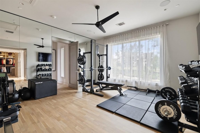 workout area featuring light wood-style floors, visible vents, and ceiling fan