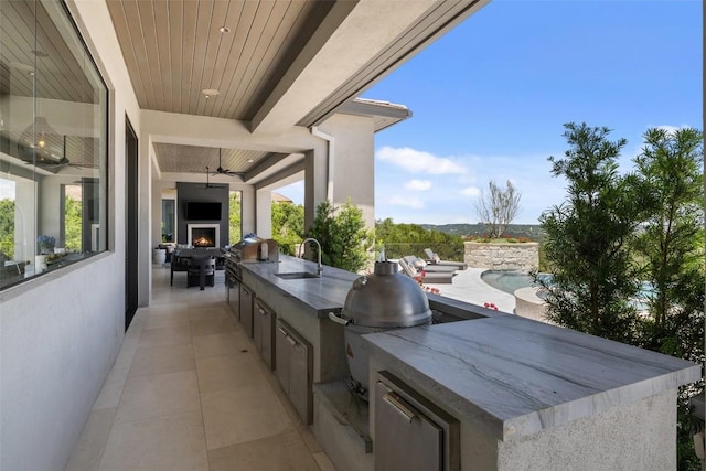 view of patio / terrace featuring a sink, grilling area, a large fireplace, exterior kitchen, and ceiling fan