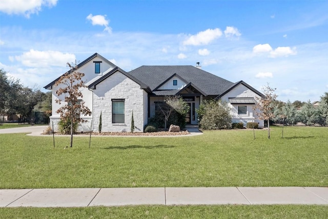 view of front facade with concrete driveway, stone siding, a shingled roof, and a front yard