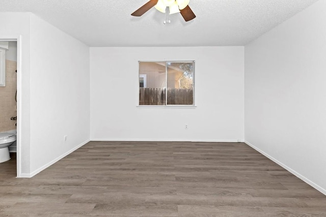 empty room featuring dark wood-type flooring, ceiling fan, and a textured ceiling