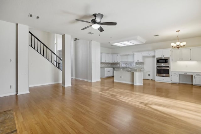 unfurnished living room featuring sink, ceiling fan with notable chandelier, and light hardwood / wood-style floors