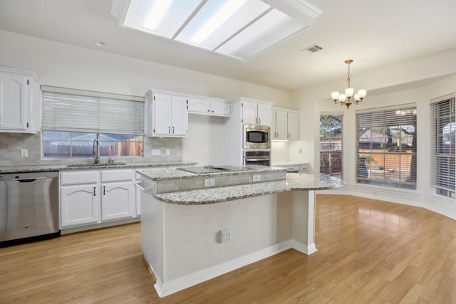 kitchen with white cabinetry, stainless steel appliances, a kitchen island, and hanging light fixtures