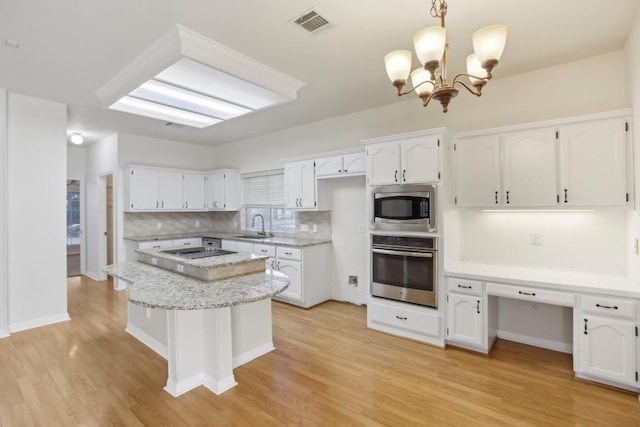 kitchen featuring tasteful backsplash, hanging light fixtures, stainless steel appliances, and white cabinets