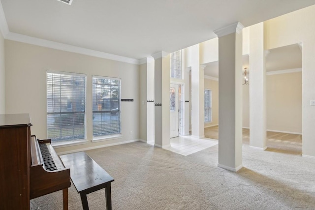 interior space featuring crown molding, light colored carpet, and ornate columns