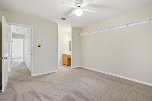 unfurnished bedroom with ceiling fan, ensuite bathroom, and light carpet