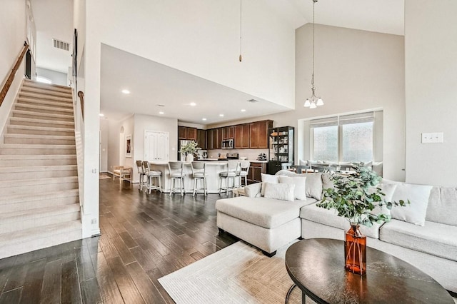 living room featuring dark wood-type flooring, a notable chandelier, and high vaulted ceiling