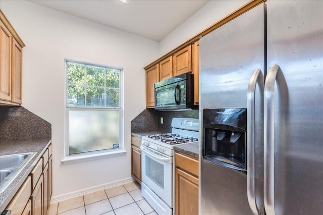 kitchen featuring sink, stainless steel fridge, backsplash, light tile patterned floors, and white gas range oven