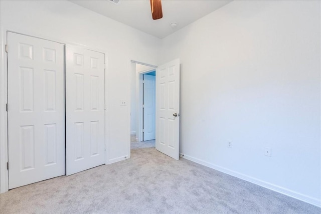 unfurnished bedroom with ceiling fan, a closet, and light carpet