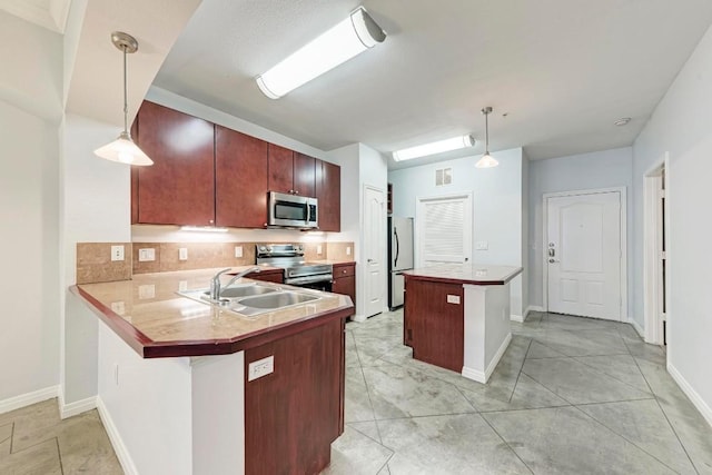 kitchen with appliances with stainless steel finishes, sink, pendant lighting, and kitchen peninsula