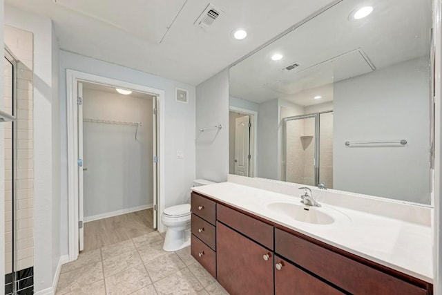 bathroom with an enclosed shower, vanity, and toilet