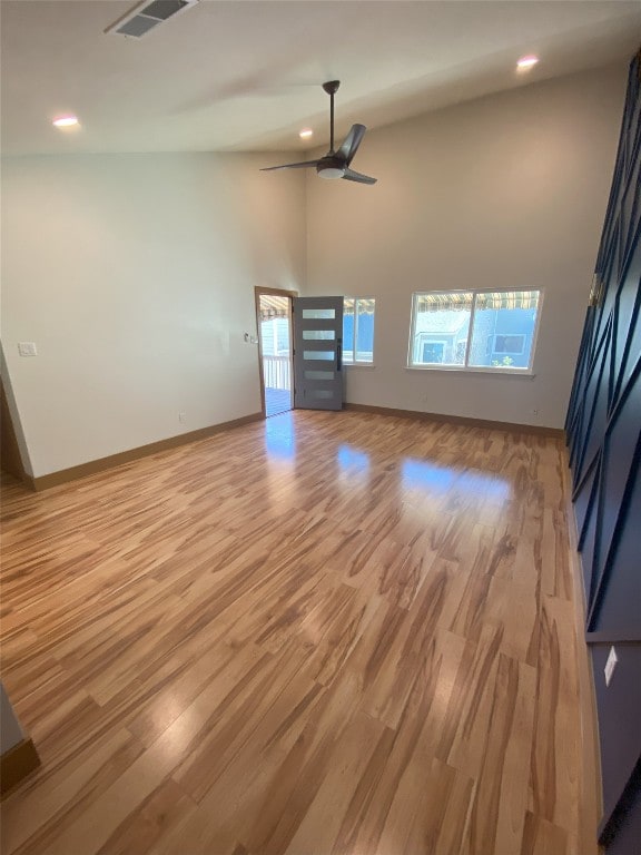 unfurnished living room featuring a towering ceiling, light hardwood / wood-style flooring, and ceiling fan