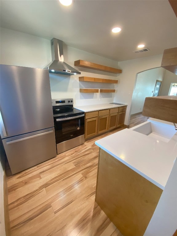 5801 Thunderbird St Unit A15, Lago Vista, TX 78645 - kitchen featuring appliances with stainless steel finishes, wall chimney range hood, light wood finished floors, brown cabinetry, and recessed lighting