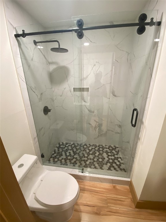 bathroom featuring toilet, hardwood / wood-style floors, and a shower with shower door