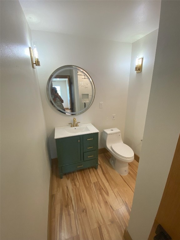 bathroom with wood-type flooring, toilet, and vanity