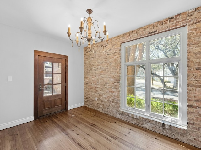 interior space featuring an inviting chandelier, hardwood / wood-style floors, and brick wall