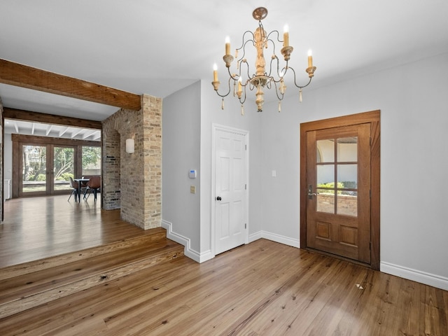 entrance foyer with french doors, beam ceiling, light hardwood / wood-style floors, and a notable chandelier