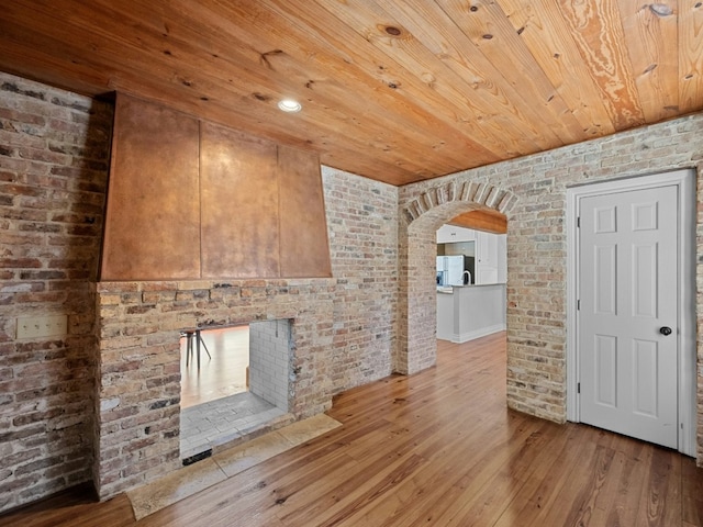 unfurnished living room with brick wall, wood-type flooring, and wooden ceiling