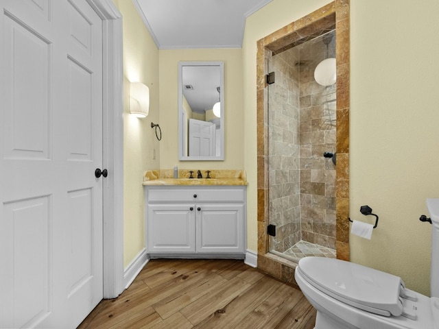 bathroom featuring hardwood / wood-style floors, vanity, ornamental molding, an enclosed shower, and toilet